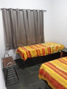 ein Zimmer mit zwei Betten und einem Vorhang in der Unterkunft Rancho M, 5Qts - Lazer para sua família em Capitólio in Capitólio + 13 Fotos