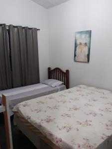 ein Schlafzimmer mit zwei Betten und einem Gemälde an der Wand in der Unterkunft Rancho M, 5Qts - Lazer para sua família em Capitólio in Capitólio
