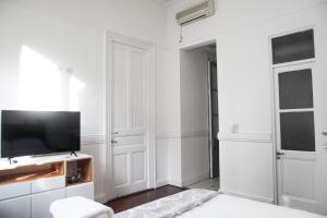 a white bedroom with a television and white walls at Inmerso Tango Hotel in Buenos Aires