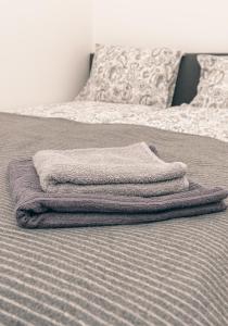 una pila di asciugamani appoggiata sopra un letto di L & S Apartmani a Sombor