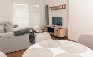 un soggiorno con tavolo e TV di L & S Apartmani a Sombor