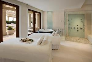 a white bedroom with two beds and a bath tub at The Breakers Palm Beach in Palm Beach