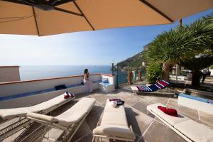 una donna in piedi su un balcone che guarda l'oceano di Luxury Seaview Villa with Jacuzzi, Sauna & Gym in Amalfi Coast - Villa Dorotea a Minori
