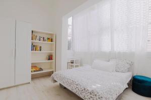 Dormitorio blanco con cama y estante de libros en Spacious 2BR Apartment with 2 Bathrooms, Living Room & Kitchen - Prime LocationNear ddizengoff st, en Tel Aviv