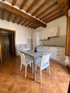 a kitchen with a table and white chairs at La Casina dell'eroe - con piscina in Gaiole in Chianti