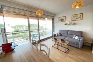 a living room with a couch and a large window at Lovely 4-person studio - pool and sea in Saint-Laurent-du-Var +10 photos