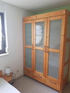 a wooden cabinet with glass doors in a bedroom at Ferienwohnung am Fuße des Poehlberg in Königswalde