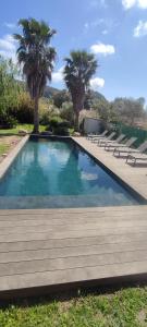 una piscina con bancos y palmeras en Villa Callochiusa avec piscine 15mn Bonifacio, en Figari