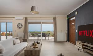 a living room with a white couch and a tv at NeSo - Peter's Flat steps to Beach with Great Views in Kolymvari