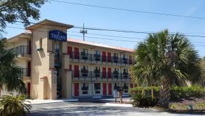 a hotel building with palm trees in front of it at Tricove Inn & Suites in Jacksonville