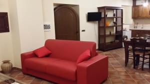 un sofá rojo en una sala de estar con mesa en Borgo Franza Case Vacanze, en Basicò
