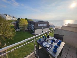 a table on a balcony with a view of the ocean at Domaine des Roches in Trouville-sur-Mer