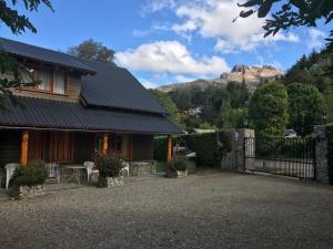 a house with a fence and mountains in the background at Duplex Ñancu Lahuen 1 Y 2 in Villa Traful