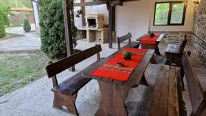 a patio with wooden benches and a table with red napkins at Къщи за гости Тепавица - Pool & Coworking in Tryavna