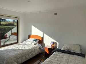 a bedroom with two beds and a window at Casa en parcelación pichilaguna, Llanquihue in Llanquihue