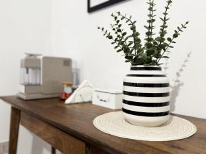 a black and white vase with a plant in it on a table at Casa Lia - Independent apartment in the Gulf of Orosei in Galtellì