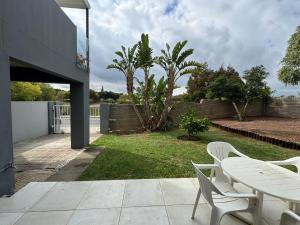 eine Terrasse mit Tisch und Stühlen in einem Hof in der Unterkunft Serene waterfront escape! Luxury, King bed! in Durbanville