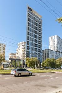 a car driving down a street with a tall building at 77 views apartments by INSHI in Lviv