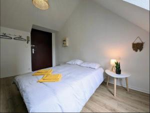 ein Schlafzimmer mit einem weißen Bett und gelben Handtüchern darauf in der Unterkunft Le calme in Saint-Brieuc + 1 Foto