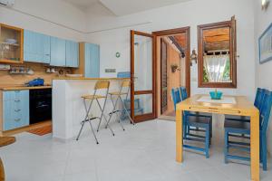 a kitchen with blue cabinets and a table and chairs at Casa del Leccio - Sea View 5 Minutes from Palau in Palau +4 photos
