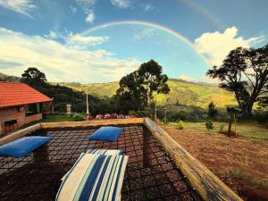 a rainbow in the sky over a patio with two beds at Belo Nascer 2 in Joanópolis