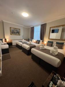 a hotel room with three beds and a couch at Tudor Court Hotel in London