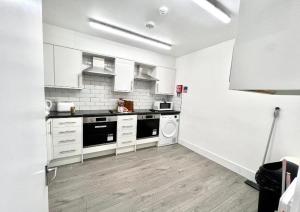 a kitchen with white cabinets and a washer and dryer at Douglas Rooms in Hayes