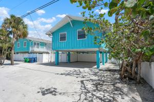 a blue house sitting on top of a beach at Hidden Treasure Unit A! Modern duplex with shared pool just 200 steps to the beach! in Bradenton Beach