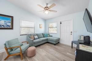 a living room with a couch and a ceiling fan at Hidden Treasure Unit A! Modern duplex with shared pool just 200 steps to the beach! in Bradenton Beach