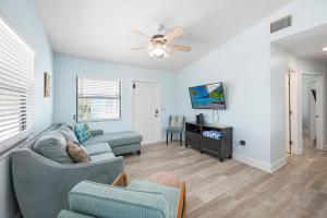 a living room with a couch and a tv at Hidden Treasure Unit A! Modern duplex with shared pool just 200 steps to the beach! in Bradenton Beach