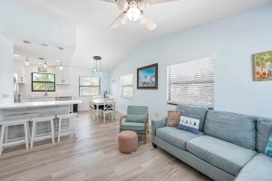 a living room with a couch and a kitchen at Hidden Treasure Unit A! Modern duplex with shared pool just 200 steps to the beach! in Bradenton Beach