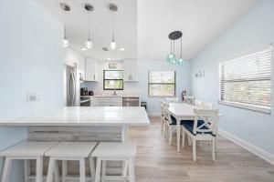 a white kitchen with a white table and chairs at Hidden Treasure Unit A! Modern duplex with shared pool just 200 steps to the beach! in Bradenton Beach
