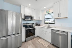 a kitchen with white cabinets and a stainless steel refrigerator at Hidden Treasure Unit A! Modern duplex with shared pool just 200 steps to the beach! in Bradenton Beach