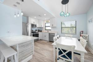 a kitchen with white cabinets and a white table and chairs at Hidden Treasure Unit A! Modern duplex with shared pool just 200 steps to the beach! in Bradenton Beach