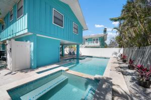 a blue house with a swimming pool in front of it at Hidden Treasure Unit A! Modern duplex with shared pool just 200 steps to the beach! in Bradenton Beach