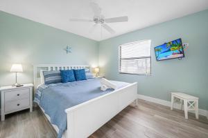 a bedroom with a bed and a ceiling fan at Hidden Treasure Unit A! Modern duplex with shared pool just 200 steps to the beach! in Bradenton Beach