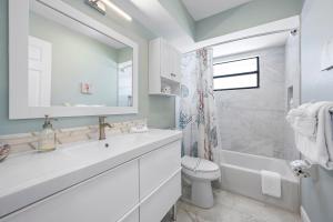 a white bathroom with a sink and a toilet at Hidden Treasure Unit A! Modern duplex with shared pool just 200 steps to the beach! in Bradenton Beach