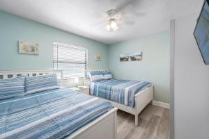 two beds in a bedroom with blue walls at Hidden Treasure Unit A! Modern duplex with shared pool just 200 steps to the beach! in Bradenton Beach