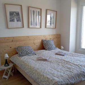 ein Bett in einem Schlafzimmer mit Bildern an der Wand in der Unterkunft La Marinière, appartement avec garage, 2 étoiles à 100m de la mer in Barneville-Carteret