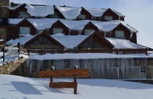 un cartel en la nieve frente a un lodge en Hotel Spa Nieves Del Cerro en Caviahue