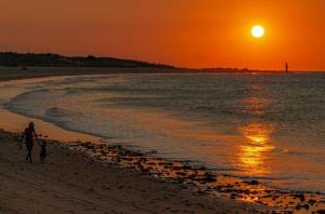 a man and a dog walking on the beach at sunset at Suites&Flats Galinhos in Galinhos