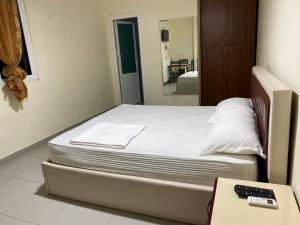 a bed in a room with a remote control at Tradita in Peqin
