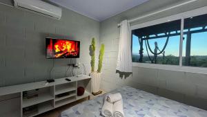 a bedroom with a bed and a tv on a wall at Loft no Morro da Borussia I in Osório