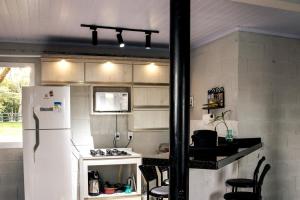 a kitchen with a white refrigerator and a stove at Loft no Morro da Borussia I in Osório
