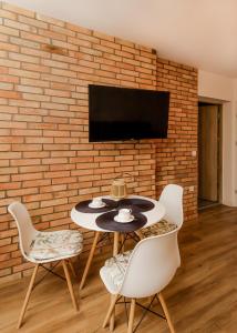a dining room with a table and chairs and a brick wall at Mieszkania na konwaliowej in Mosty