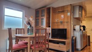 a dining room with a table and a tv and a kitchen at Joli Mobilhome 4 personnes proche Mimizan océan et lac in Sainte-Eulalie-en-Born