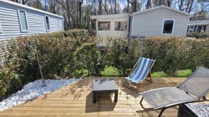 a wooden deck with two chairs and a table at Joli Mobilhome 4 personnes proche Mimizan océan et lac in Sainte-Eulalie-en-Born