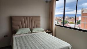 a bedroom with a bed and a large window at Beautiful and central apartment in Tarija