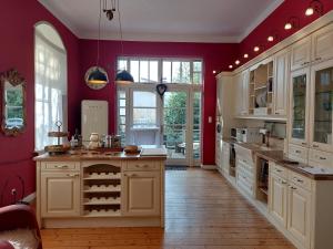 a large kitchen with red walls and white cabinets at Villa Elisabeth 1905 in Bad Harzburg