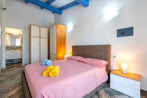 Un dormitorio con una cama rosa con almohadas amarillas. en Villetta Jolanda-Valledoria, en Valledoria